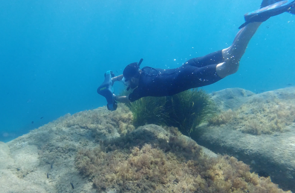 Un plongeur sous l'eau se promenant avec un scooter sous marin de notre partenaire Splura